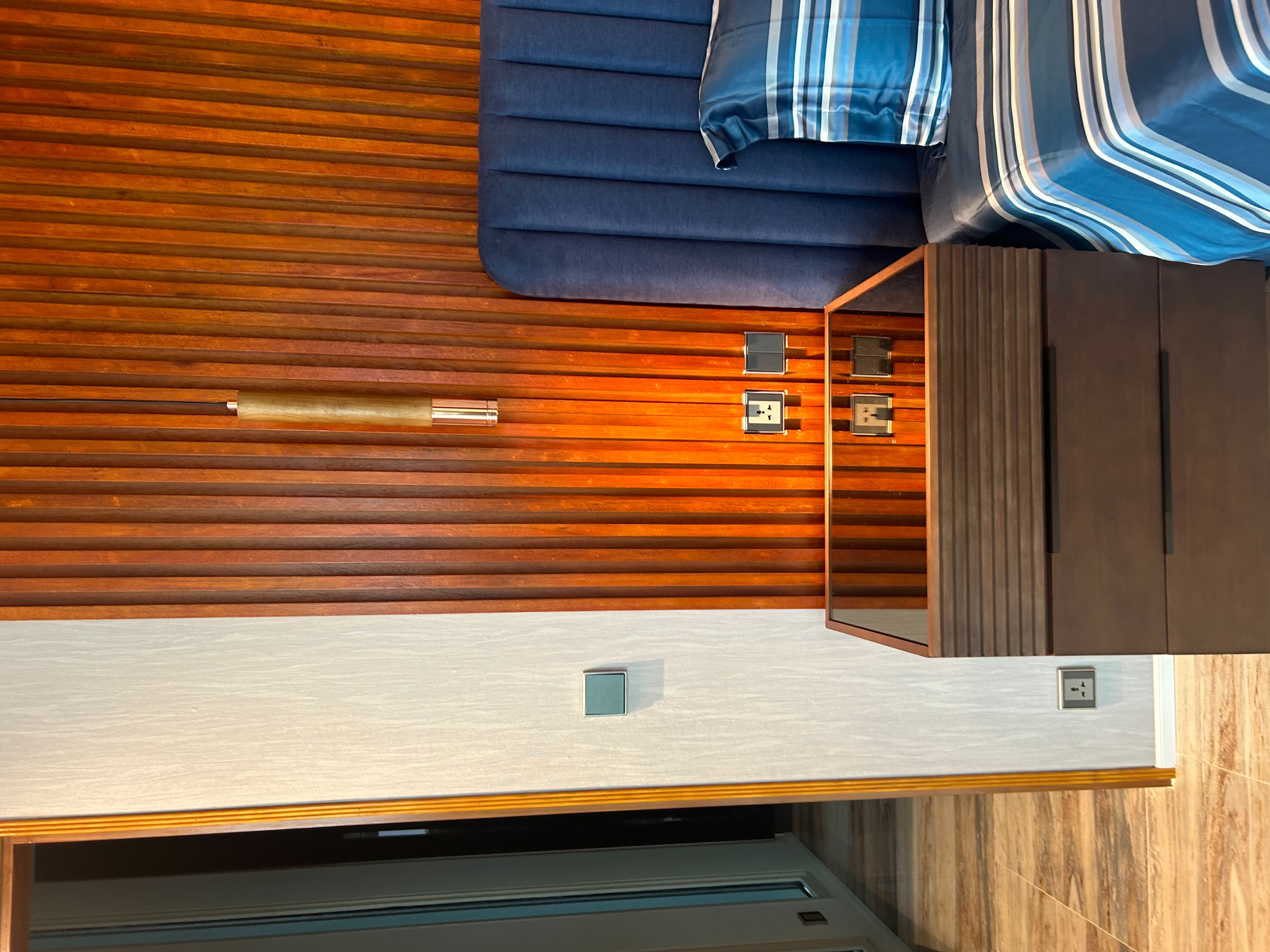 Bedroom with custom wood slat accent wall and integrated bedside storage