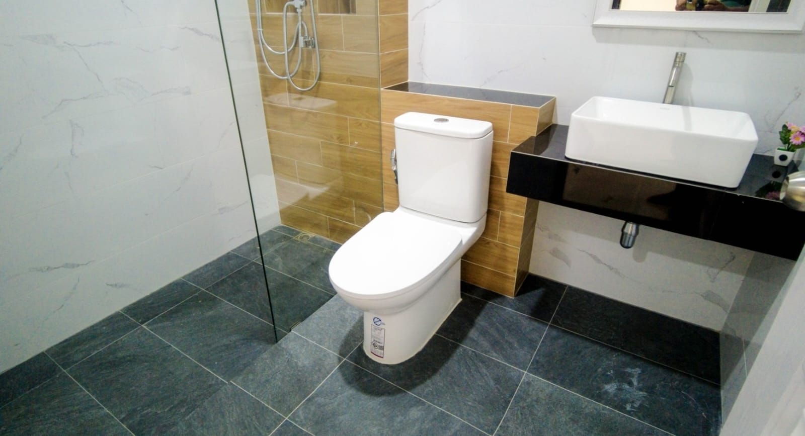 Contemporary bathroom with wood-look tiles, marble flooring, and glass shower partition