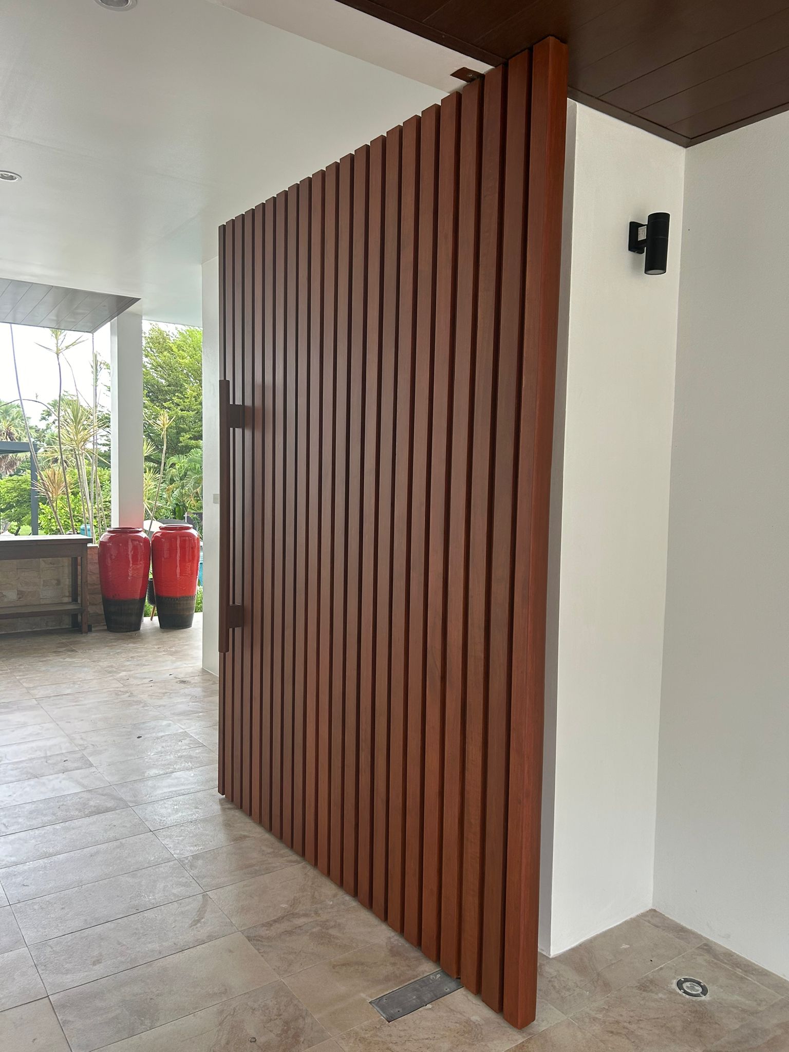 Custom wooden slat privacy door with modern hardware in outdoor covered area