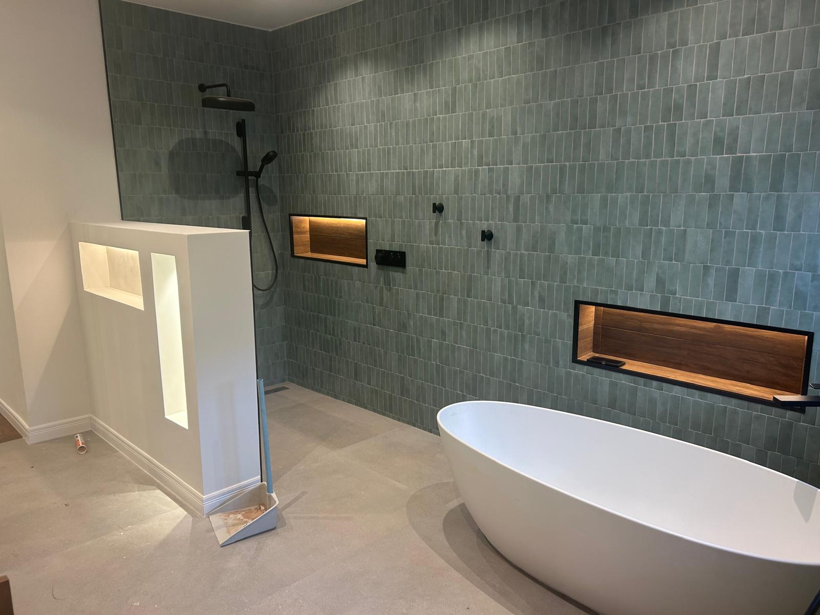 Luxury spa-style bathroom with sage green subway tiles and freestanding bathtub