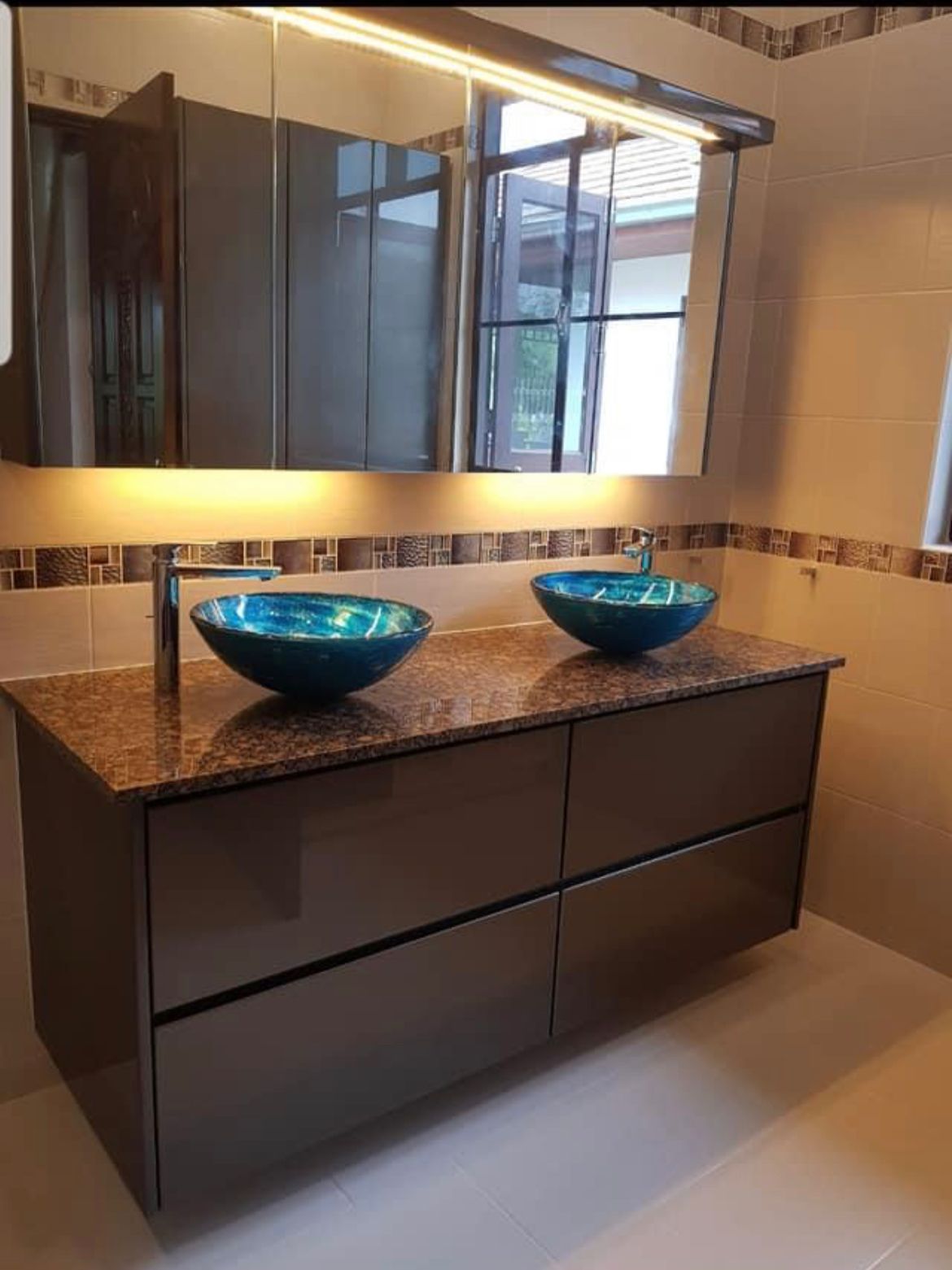Modern double vanity bathroom with blue glass vessel sinks and granite countertops
