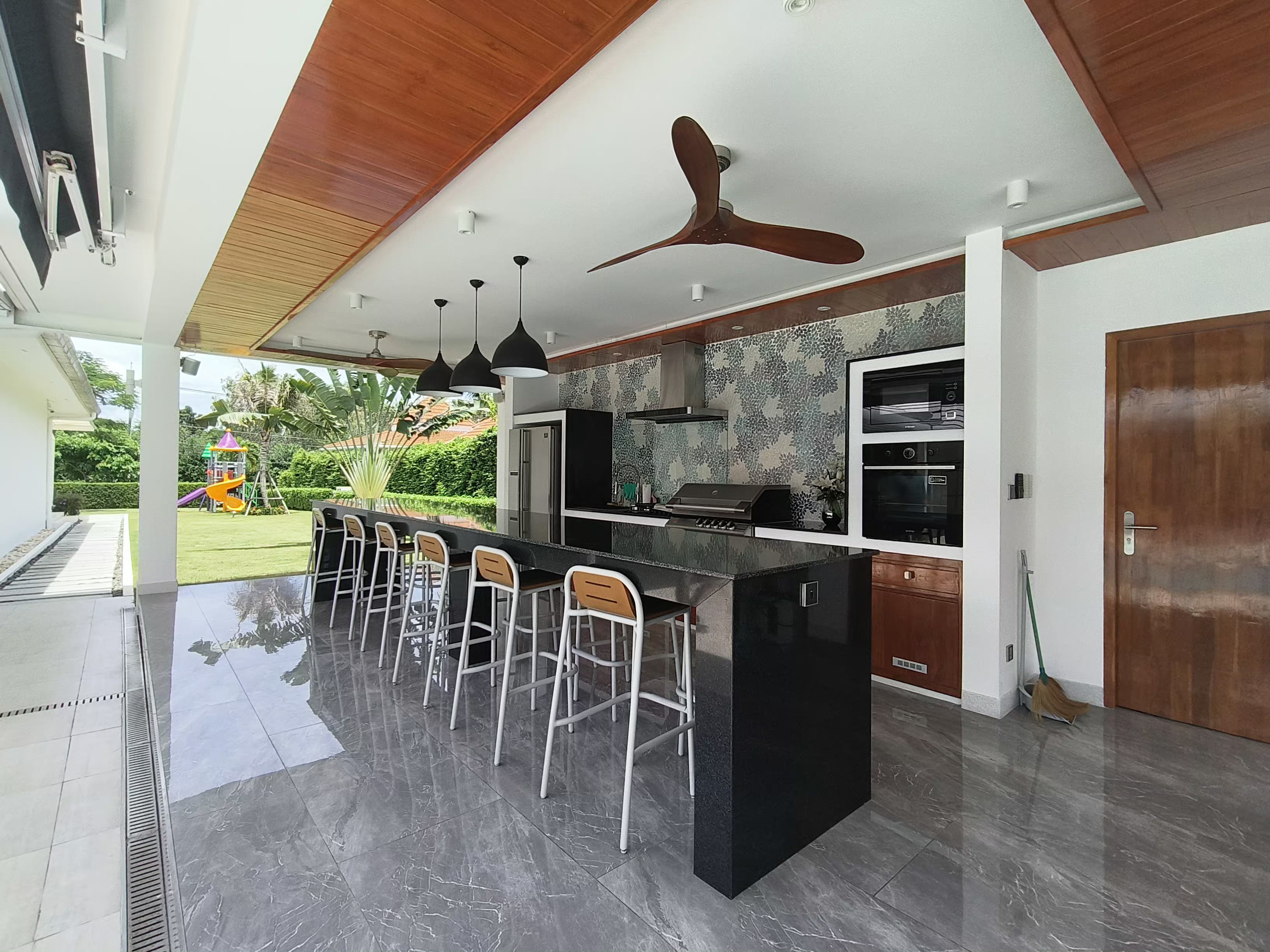Luxury outdoor kitchen with black marble island and wood beam ceiling